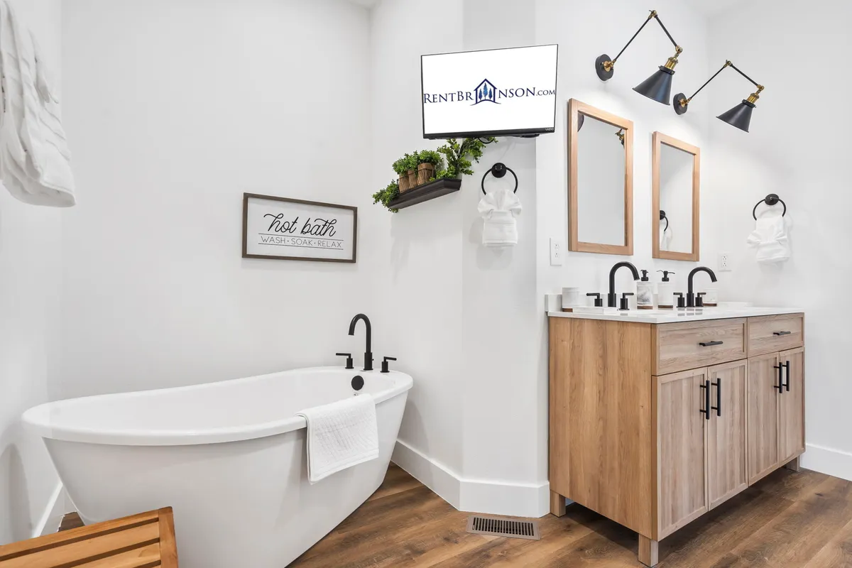A luxurious bathroom with a freestanding bathtub, dual vanity with mirrors and elegant lighting, and a wall-mounted TV. The decor is modern yet calming, creating a spa-like atmosphere ideal for self-care and relaxation.