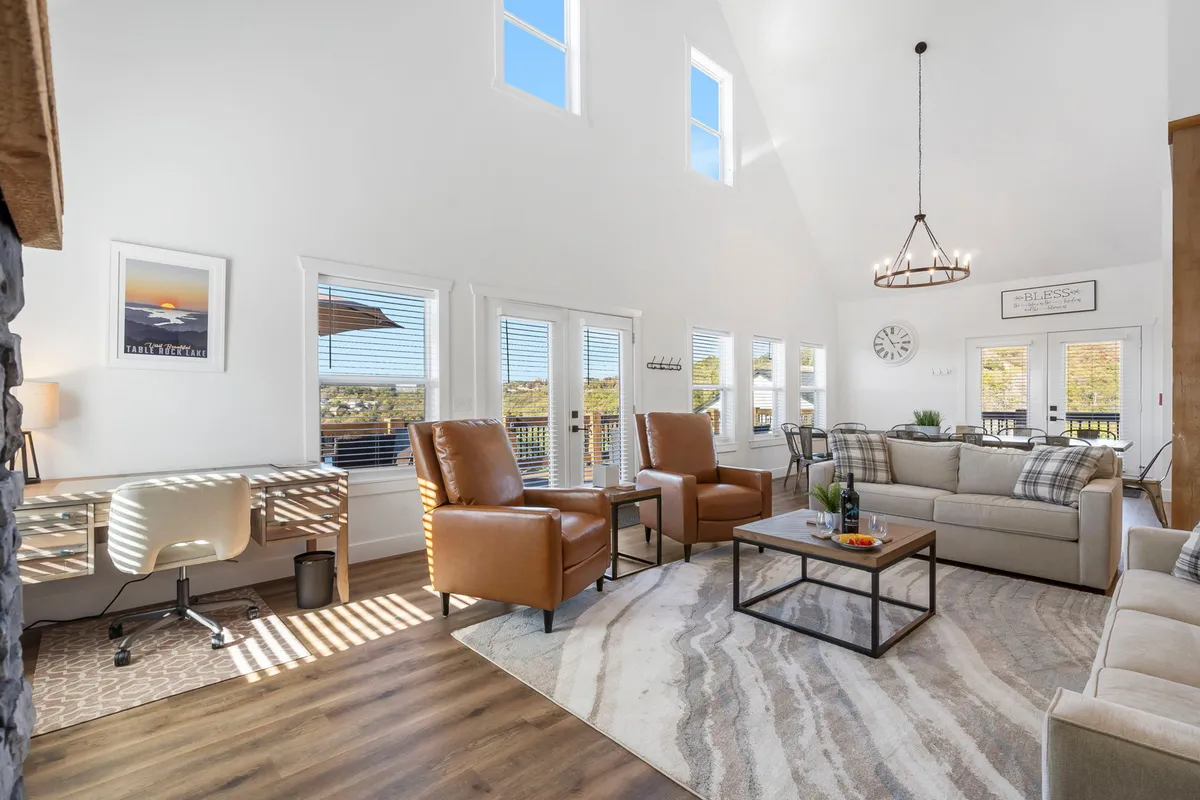 A sunlit interior lounge with large windows that bring in natural light and offer glimpses of the outdoors. Comfortable leather armchairs and a stylish coffee table create a cozy spot for relaxing with a book or sharing a quiet morning coffee together, with decorative art adding a touch of sophistication.